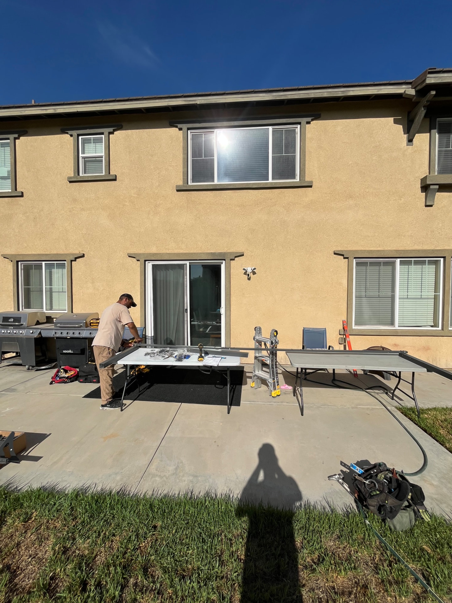 Bare backyard concrete patio with the old cover removed and the crew laying out framing material