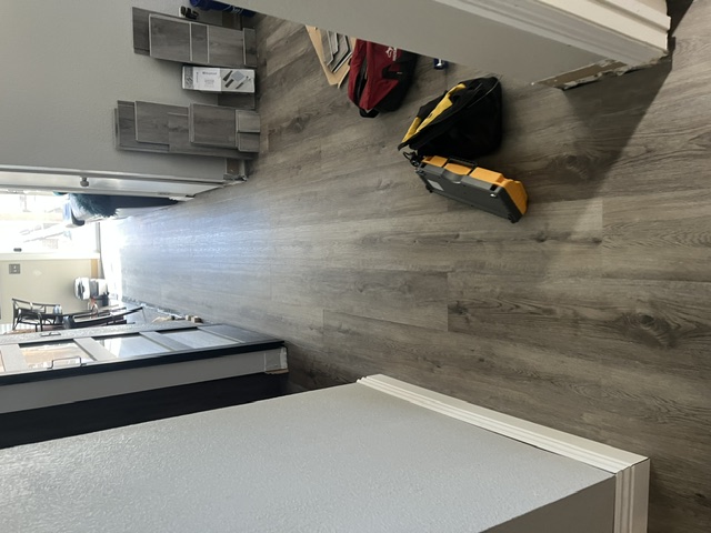 Same hallway with new gray wood-look vinyl plank flooring and fresh white baseboard