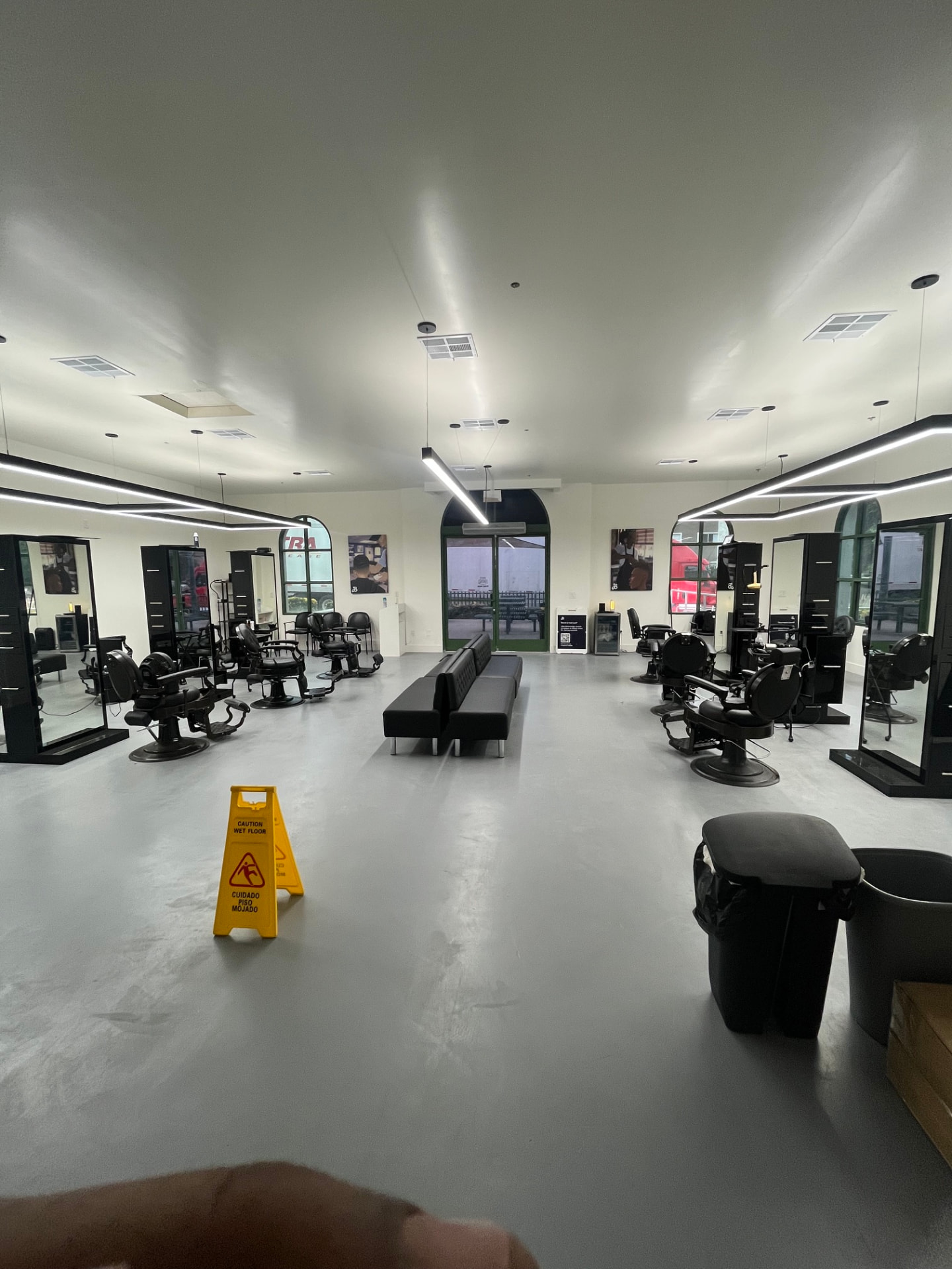 Finished barber shop with polished floors, linear lighting, mirrors, and barber chairs in place