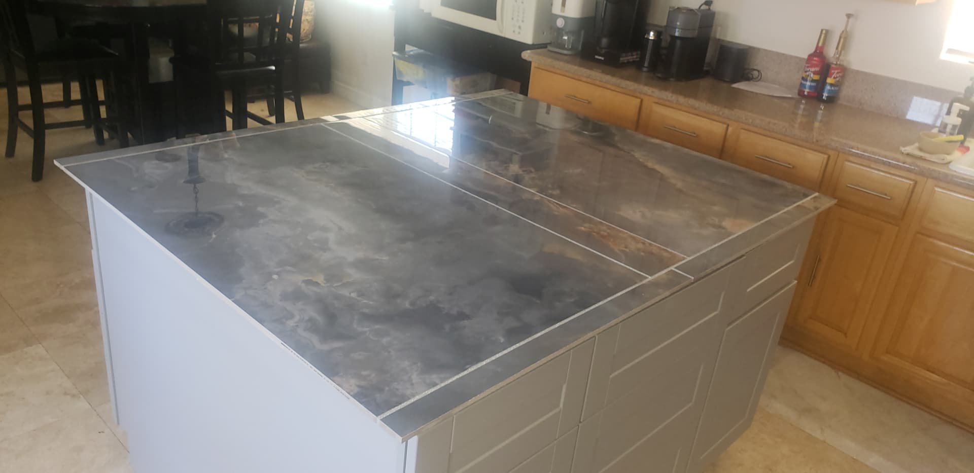 New built-in kitchen island with white shaker cabinetry and a dark marbled porcelain countertop