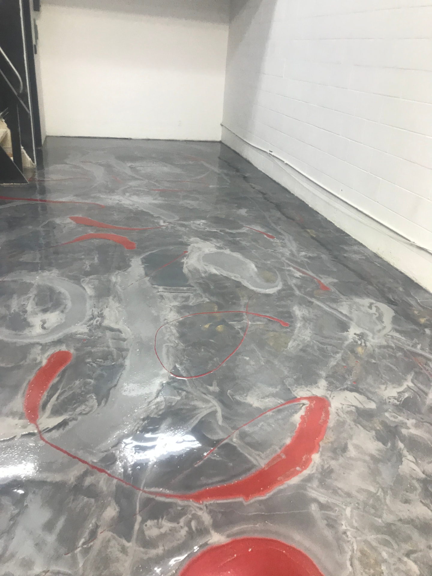 Finished metallic epoxy floor with gray marbled swirls and red accent lines