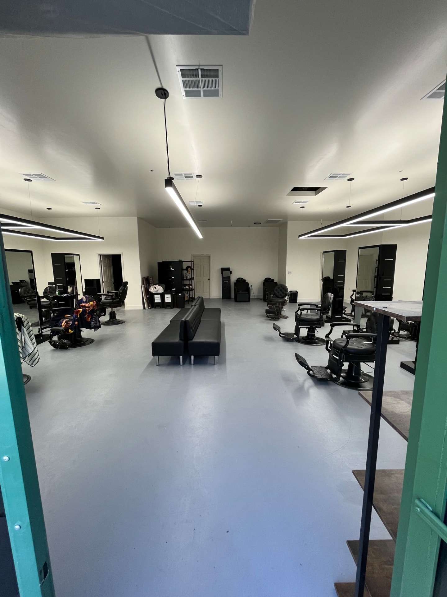 Finished barber shop with painted walls, linear lighting, mirrors, and barber chairs installed