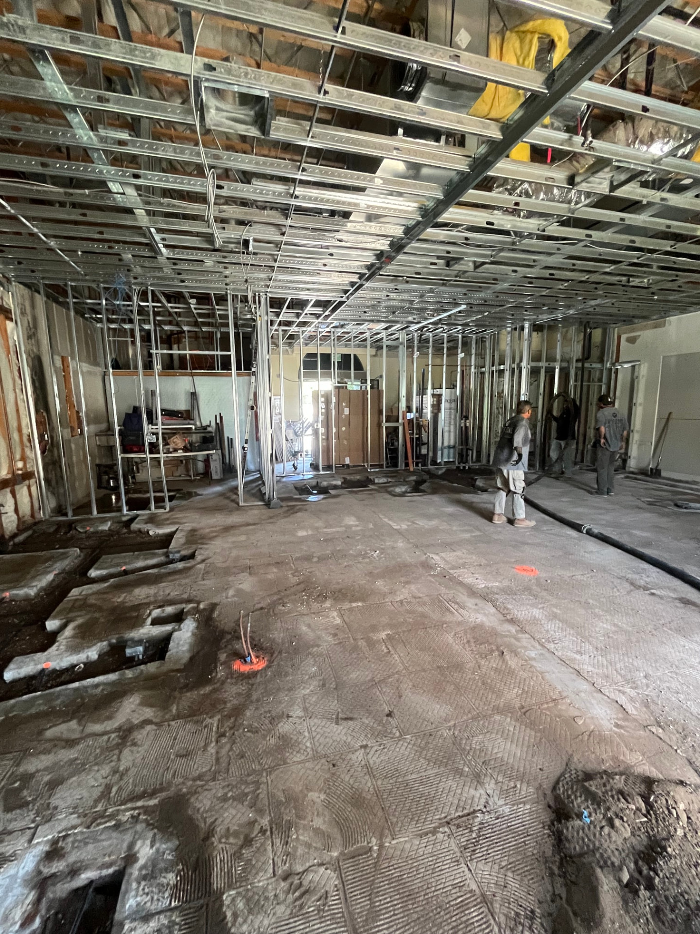 Commercial space gutted to bare concrete with steel stud walls and ceiling grid framed out