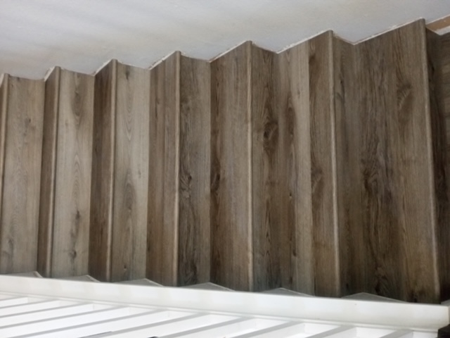 Finished vinyl plank staircase with wood-look treads and white railing