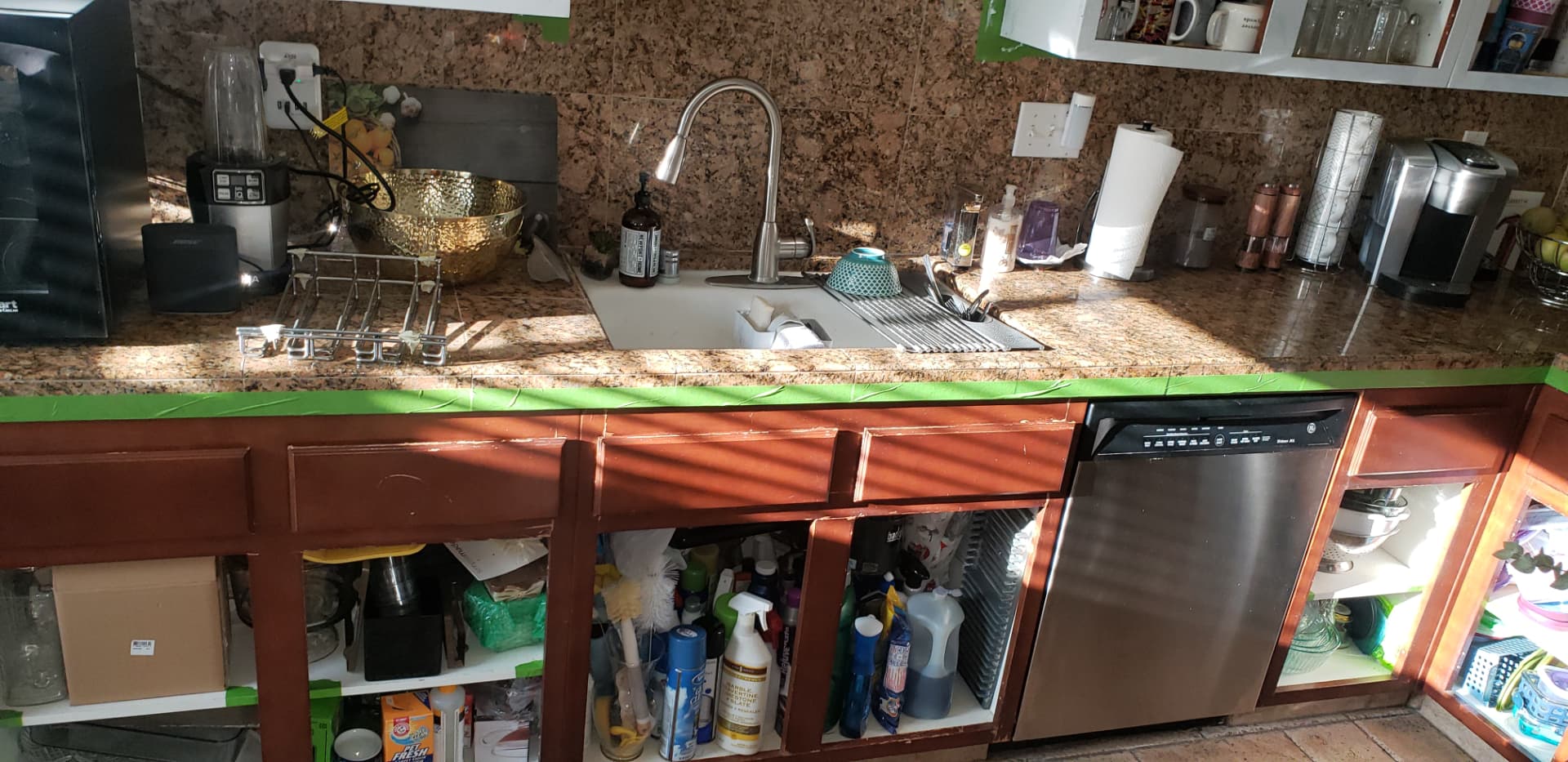 Kitchen sink and dishwasher cabinet run in worn dark cherry finish before the remodel
